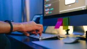 Mobile developer writes program code on a computer, typing on keyboard