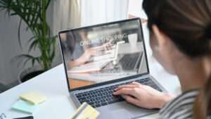 View over shoulder young woman holding credit card and shopping online on E-commerce website. View over shoulder young woman holding credit card and shopping online on E-commerce website.